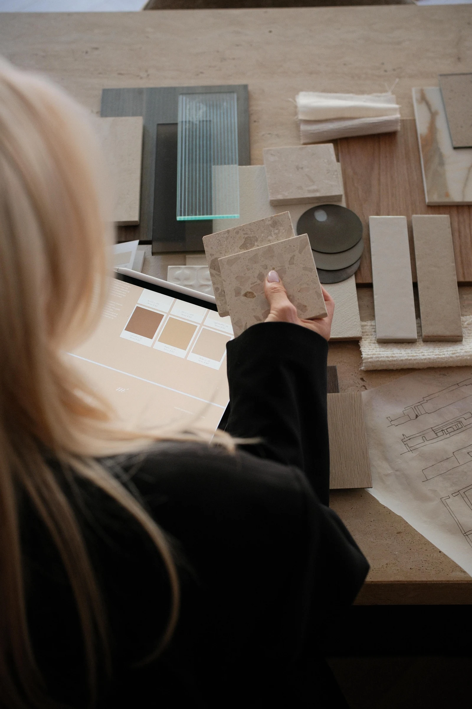 Rianne bekijkt materiaalstalen en een interieurconcept in het atelier.