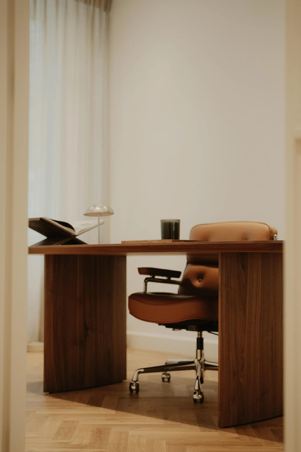 Houten bureau met afgeronde vormen en een cognackleurige stoel, zoals getoond in de ontwerpreferentie.